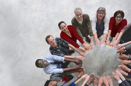 Gruppe von Menschen bildet mit ihren Händen einen Kreis.